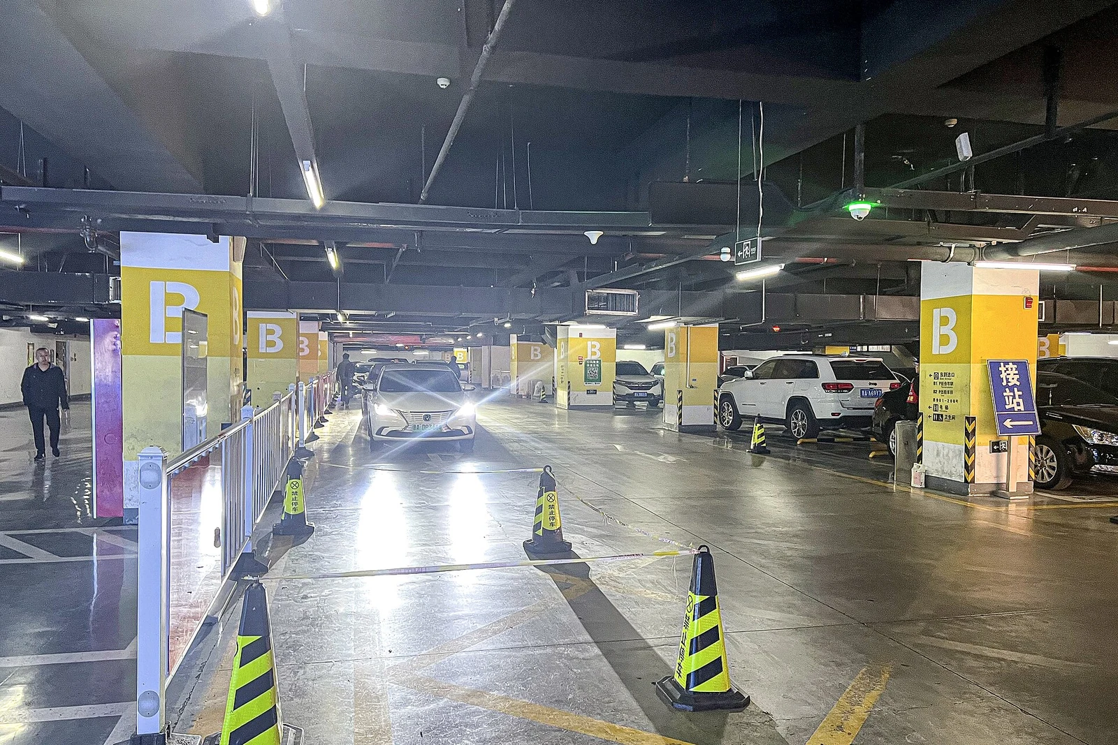 Zona señalizada de recogida de coches solicitados por aplicación en un aparcamiento cubierto.