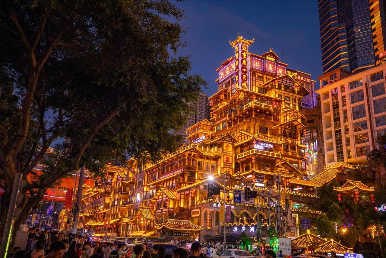 Hongya Cave iluminada por la noche junto al río en Chongqing
